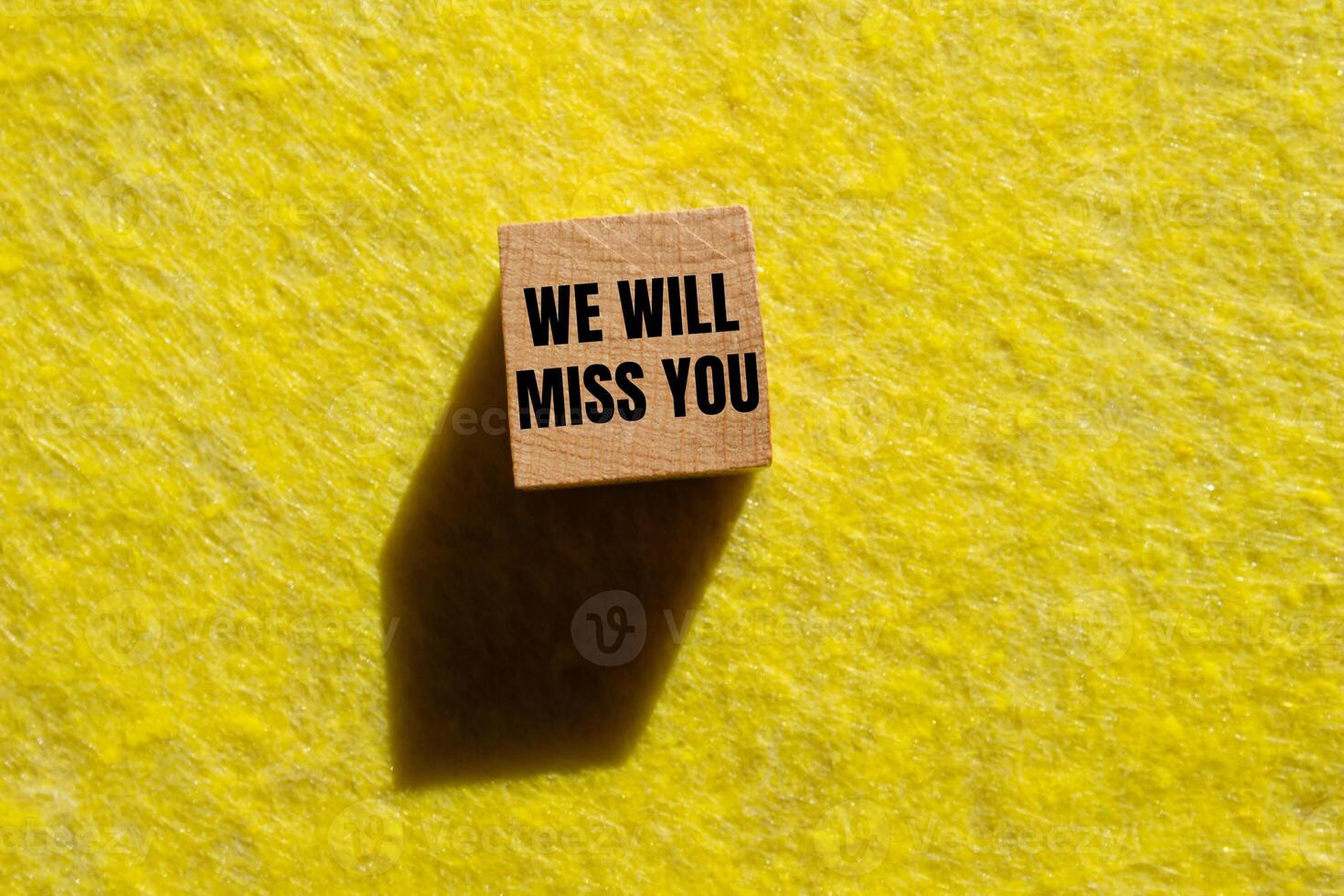We will miss you message written on wooden cube with yellow background. Conceptual we will miss you symbol. Copy space. photo