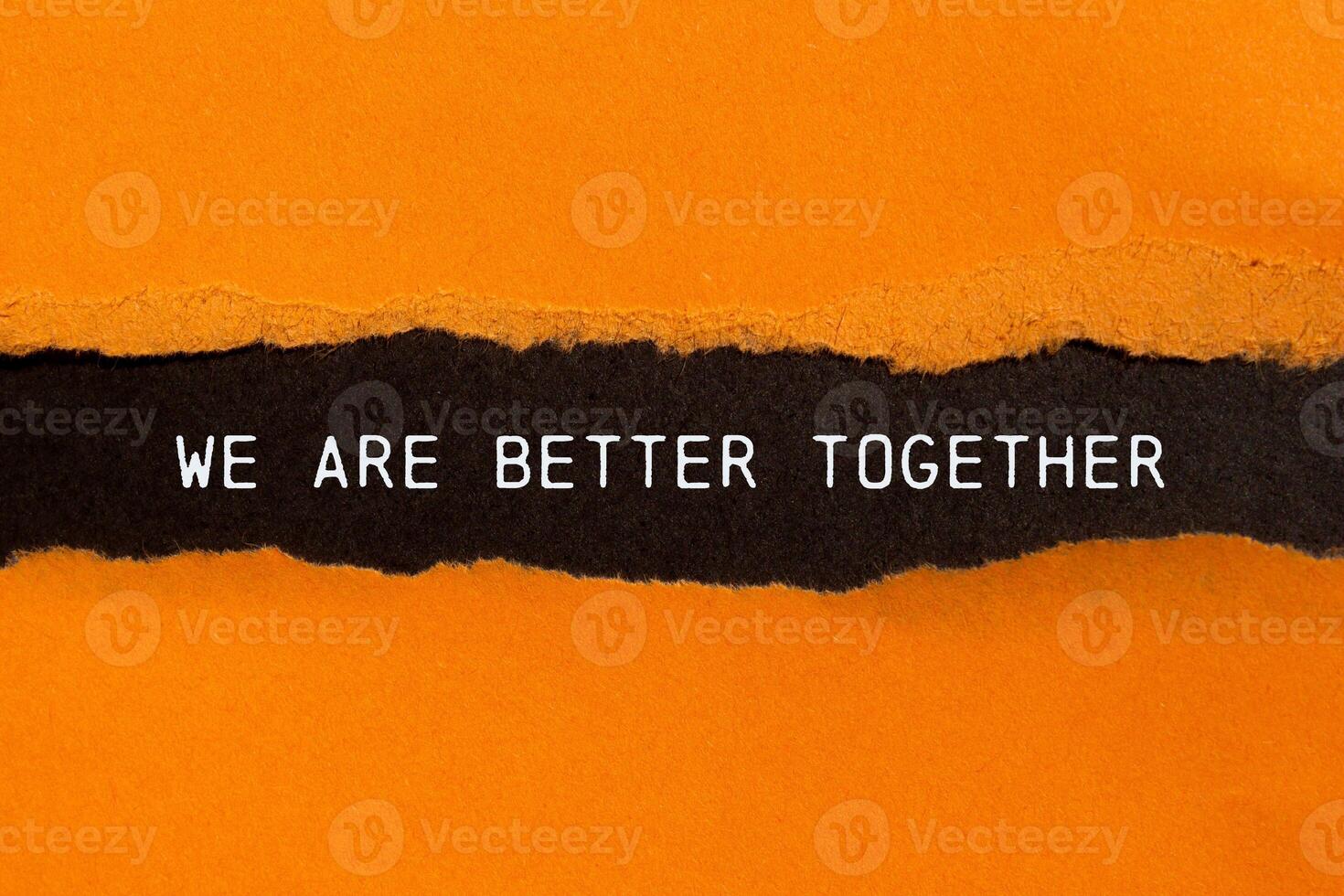 We are better together message written on ripped torn orange paper on black background. Conceptual we are better together symbol. Copy space. photo