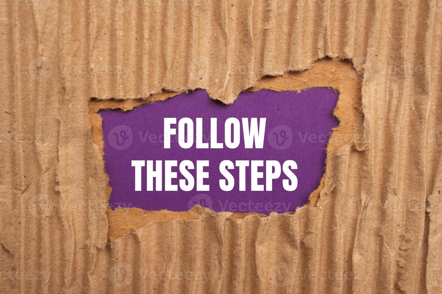 Follow these steps message written on ripped torn cardboard paper on purple background. Conceptual follow these steps symbol. Copy space. photo