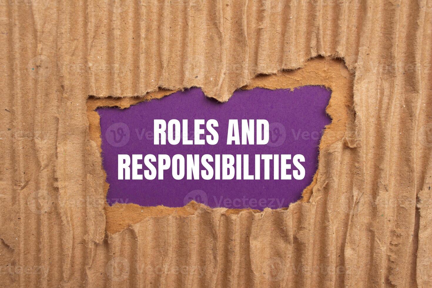Roles and responsibilities message written on ripped torn cardboard paper on purple background. Conceptual roles and responsibilities symbol. Copy space. photo