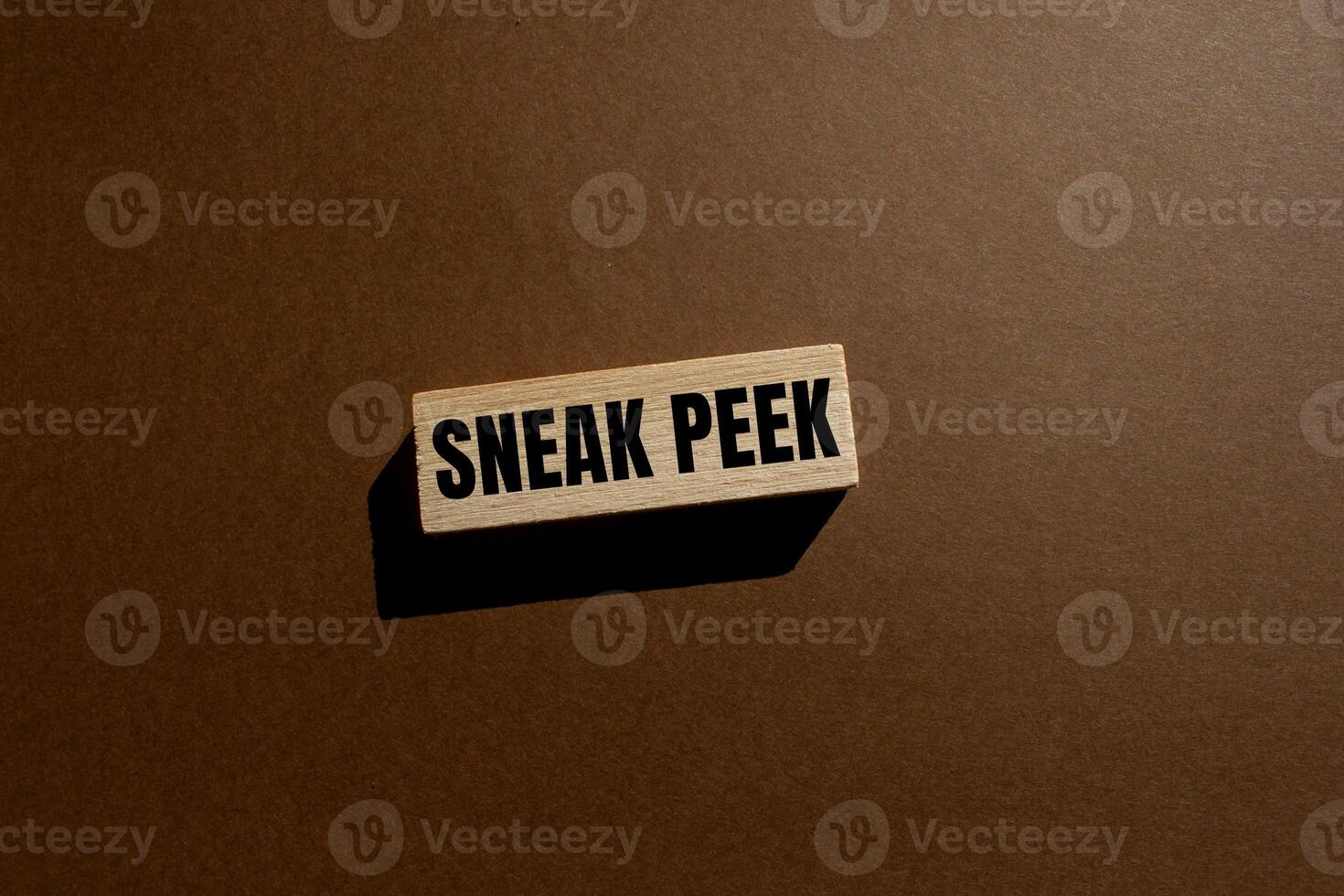 Sneak peek message written on wooden block with brown background. Conceptual sneak peek symbol. Copy space. photo