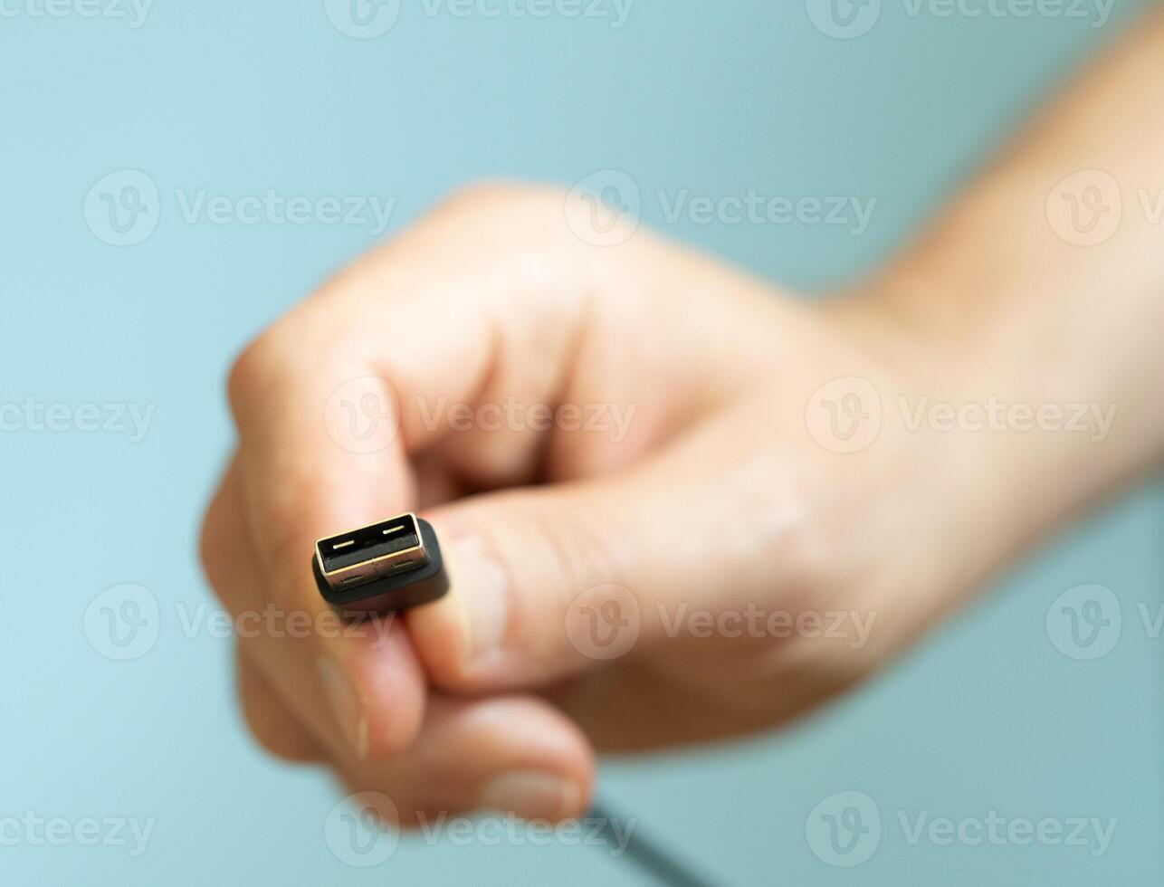 a person holding different usb cable on a plain blue background photo
