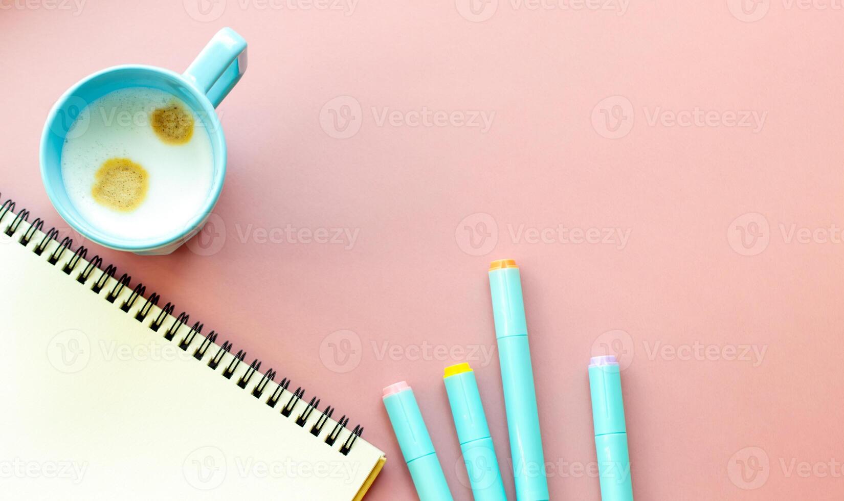 Perfect for themes related to education, art, and office aesthetic, pastel colors. colored highlighters, sketchbook, coffee mug on a plain pink background photo