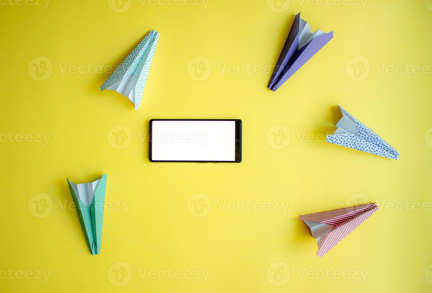 paper airplanes chaotically circle around the phone. abstraction on the theme of messages and communication photo