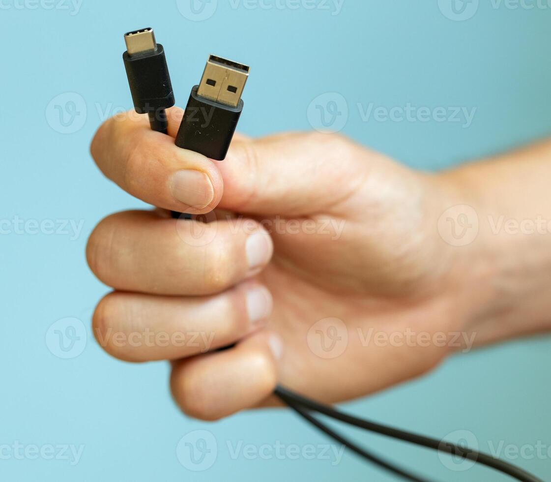 a person holding different usb cable on a plain blue background photo