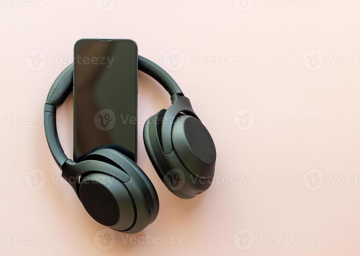 wireless headphones and smartphone on a plain pink background. music and entertainment, phone screen photo