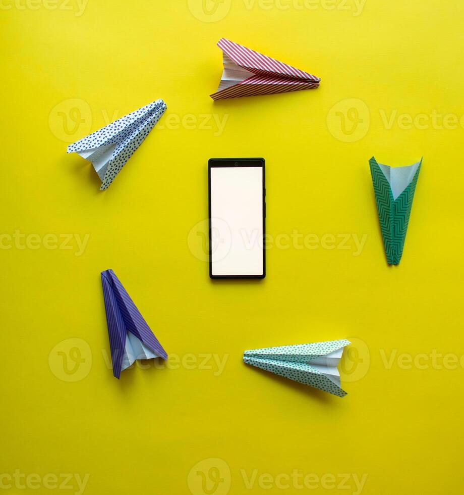 paper airplanes chaotically circle around the phone. abstraction on the theme of messages and communication photo