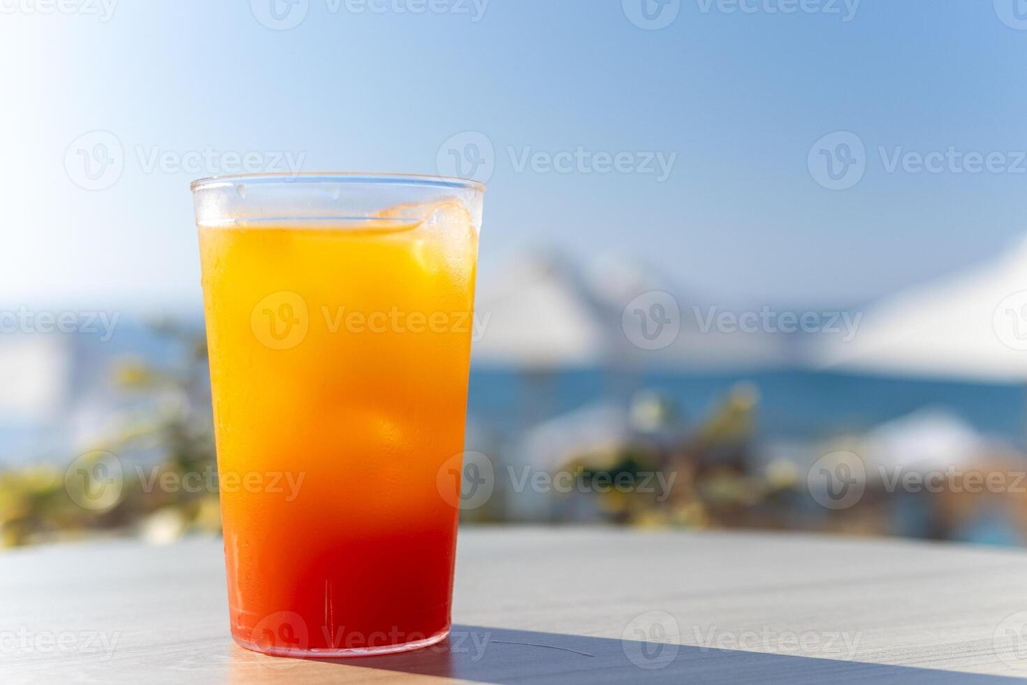 refreshing bright cocktail with ice against the backdrop of sun loungers and the sea photo