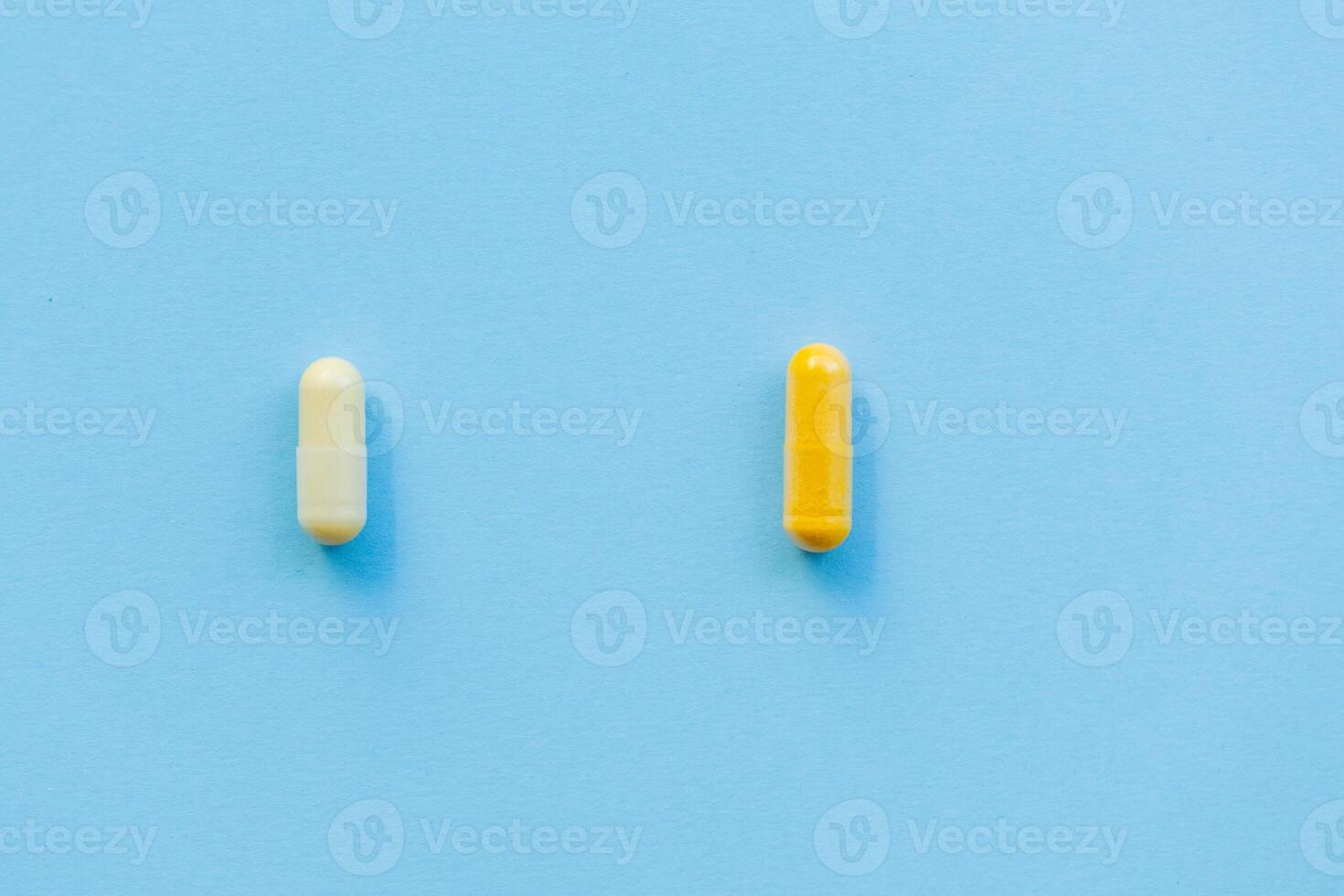 two tablets of different colors yellow and white on a plain blue background, drug or medical addiction, choosing the right and wrong pill photo