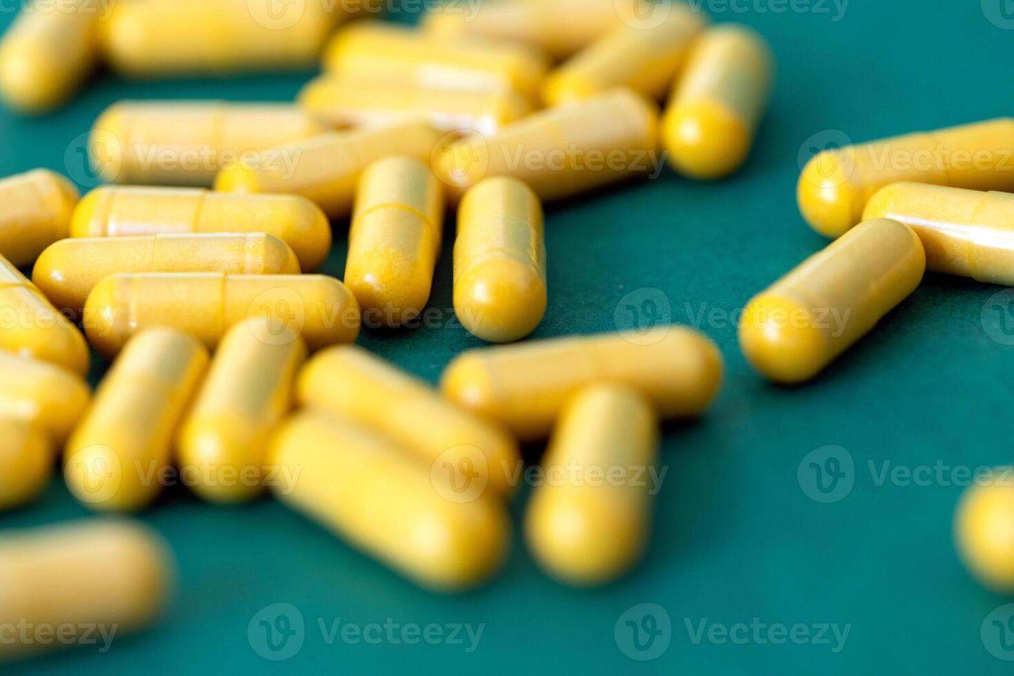 handful of yellow medical capsules on dark green plain background photo