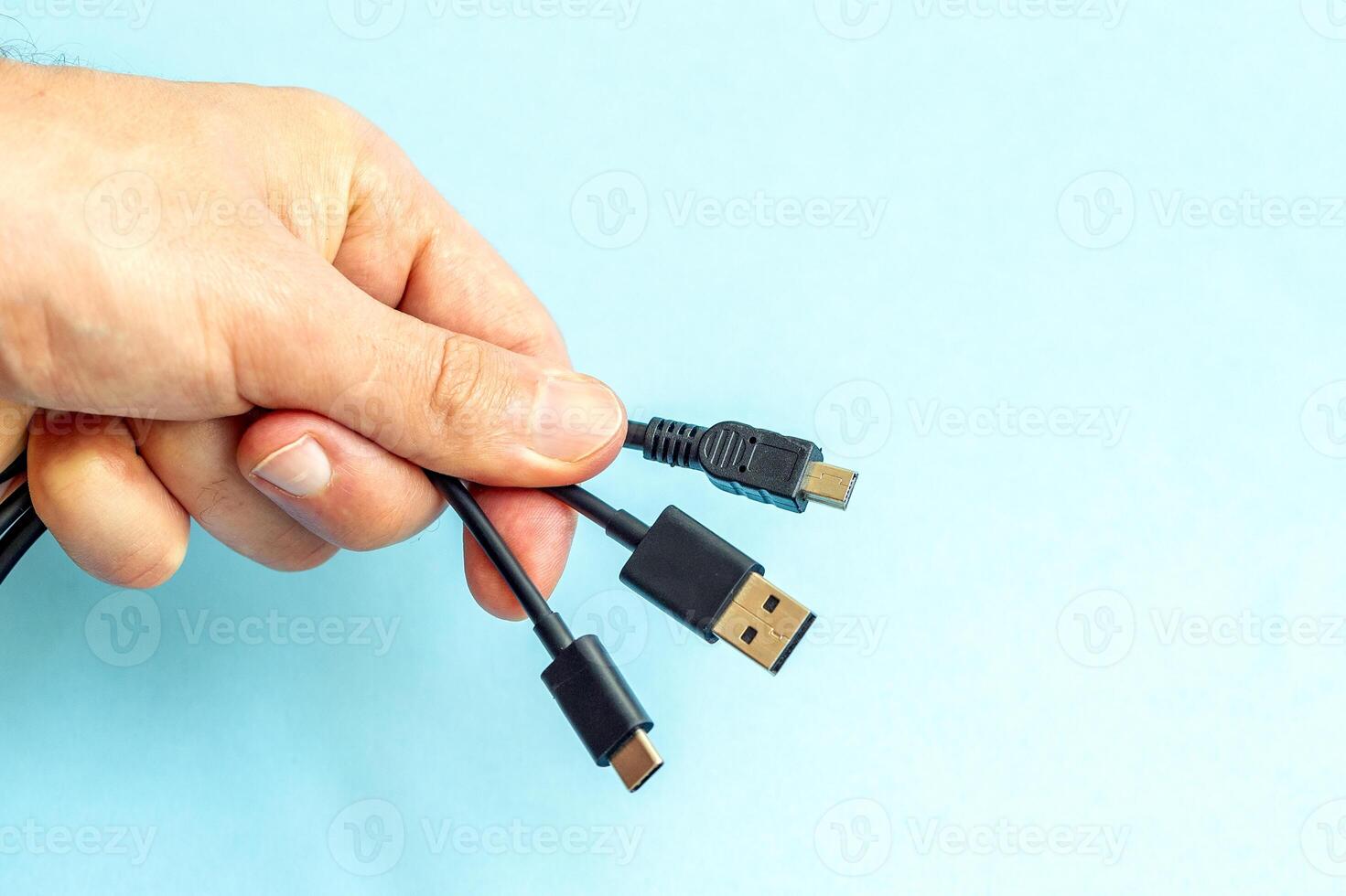 a person holding different usb cable on a plain blue background photo