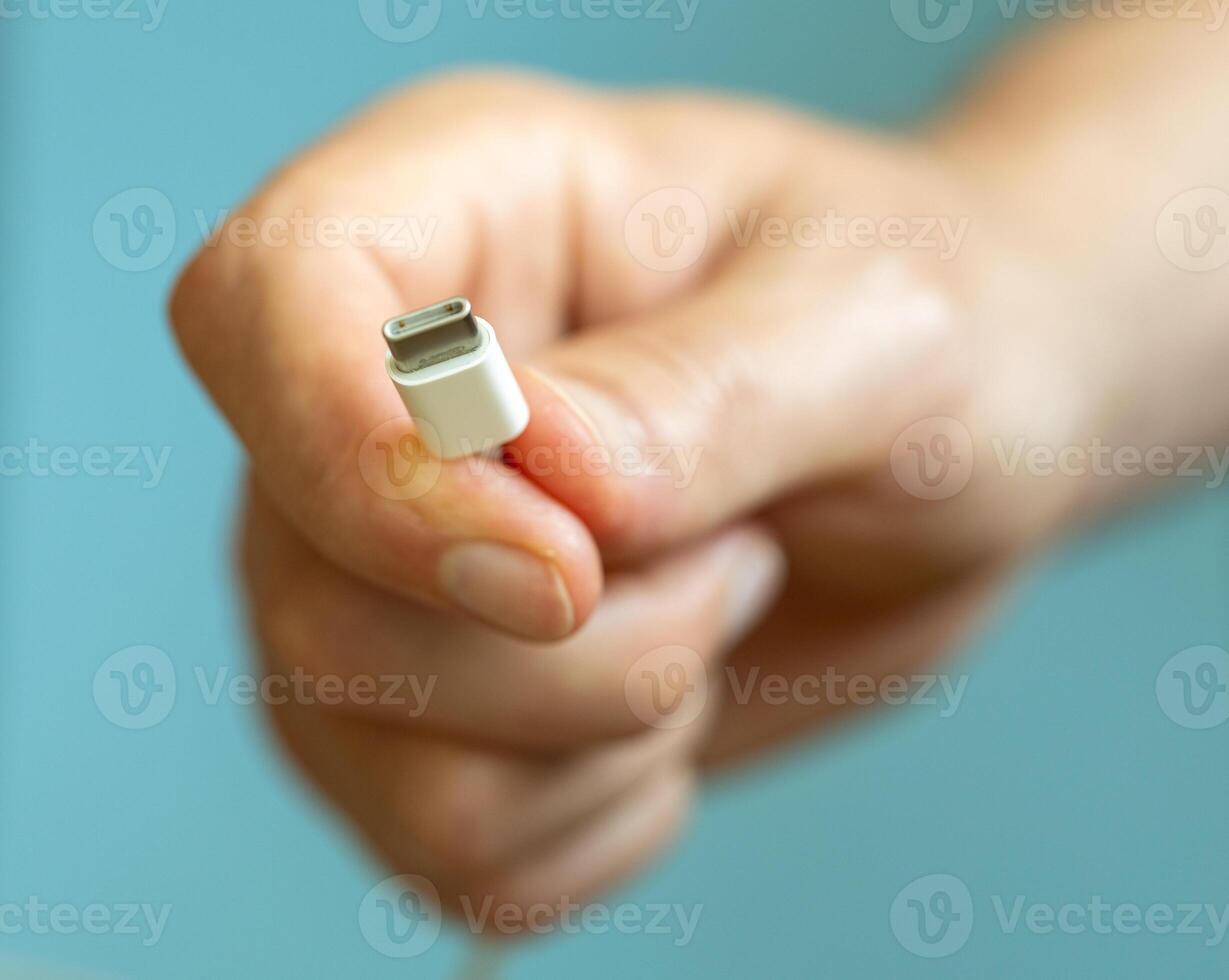 a person holding different usb cable on a plain blue background photo