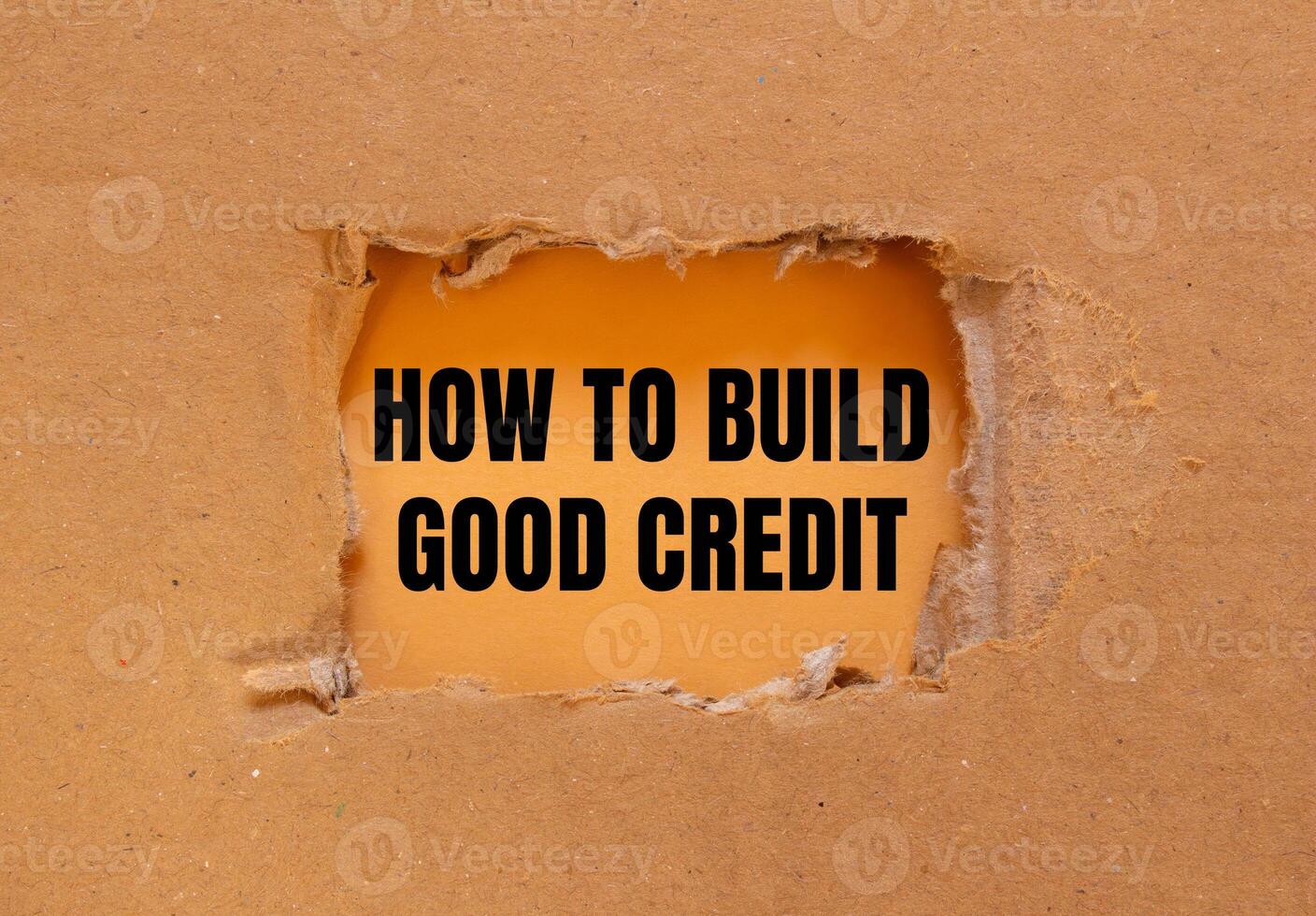 How to build good credit message written on ripped torn cardboard paper with orange background. Conceptual how to build good credit symbol. Copy space. photo