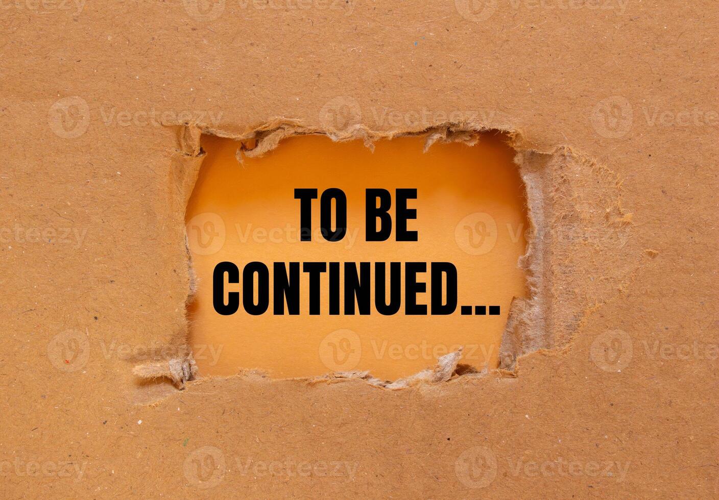 To be continued message written on ripped torn cardboard paper with orange background. Conceptual to be continued symbol. Copy space. photo