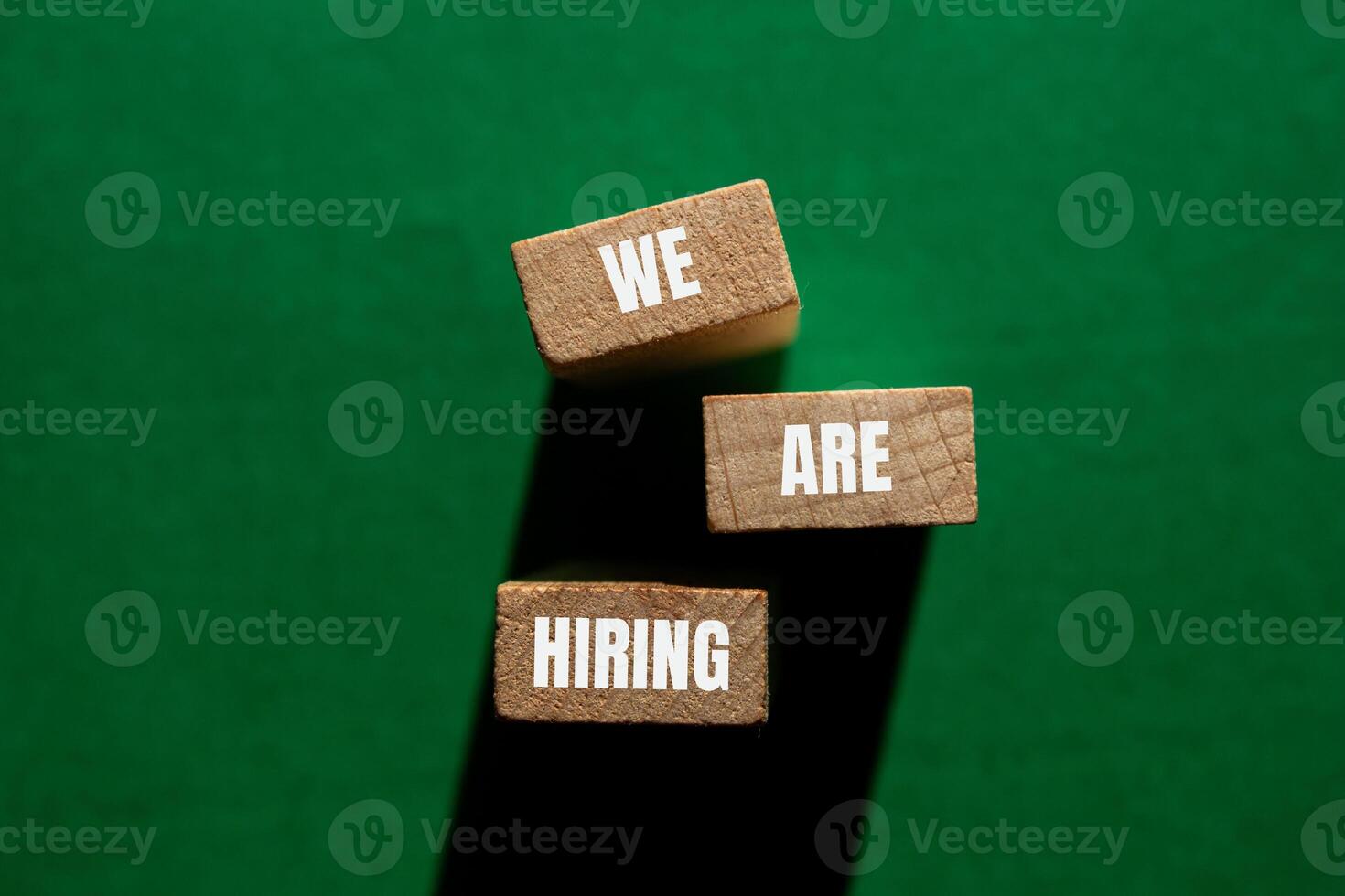 We are hiring message written on wooden blocks with green background. Conceptual we are hiring symbol. Copy space. photo