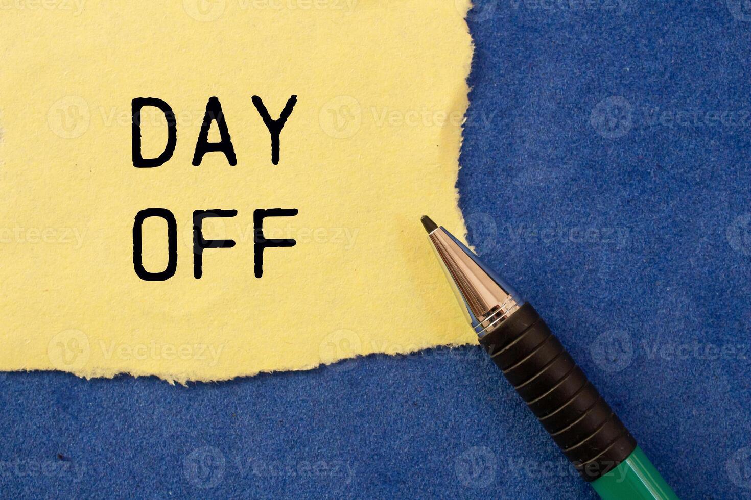 Day off message written on ripped torn yellow paper with a pen on blue background. Conceptual day off symbol. Copy space. photo