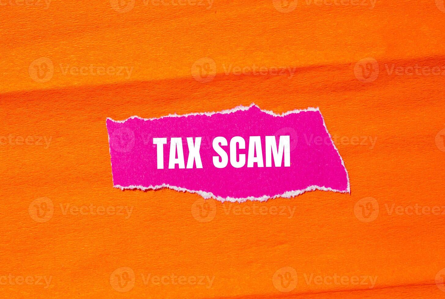 Tax scam message written on ripped torn pink paper with orange background. Conceptual tax scam symbol. Copy space. photo