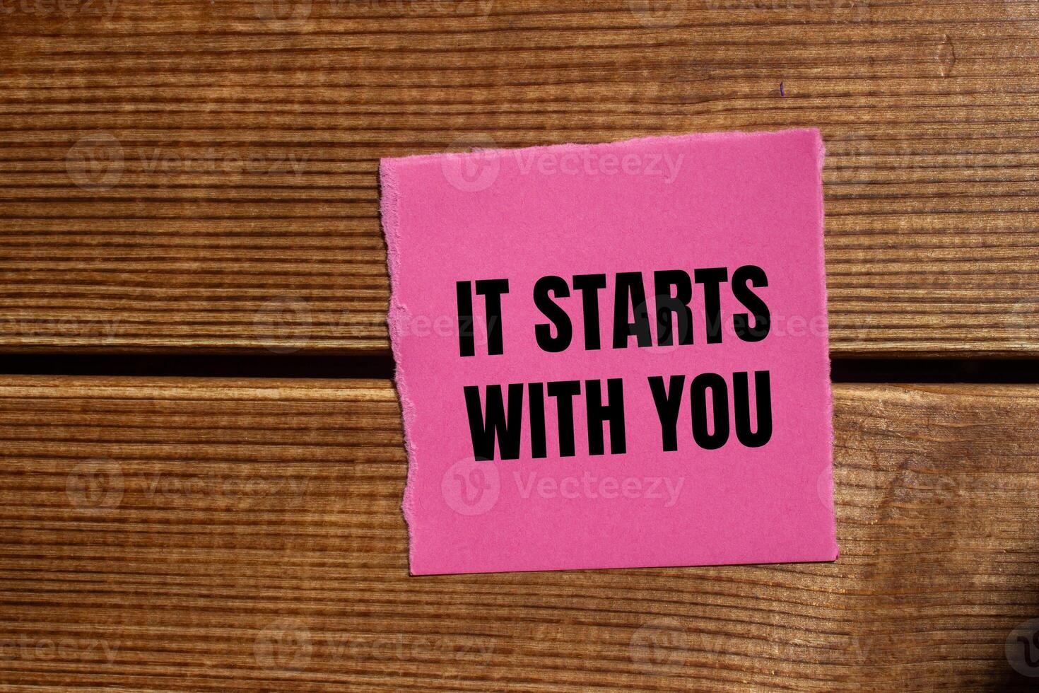 It starts with you message written on ripped torn pink paper piece with wooden background. Conceptual it starts with you symbol. Copy space. photo