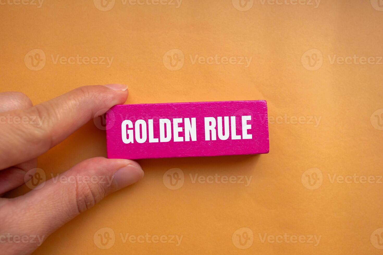 Golden rule message written on pink wooden block with orange background. Conceptual golden rule symbol. Copy space. photo