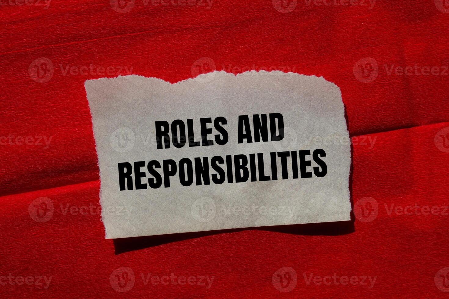 Roles and responsibilities message written on ripped torn paper piece on red background. Conceptual roles and responsibilities symbol. Copy space. photo
