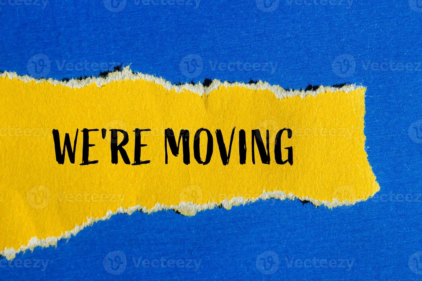 We are moving message written on ripped torn yellow paper with blue background. Conceptual we are moving symbol. Copy space. photo