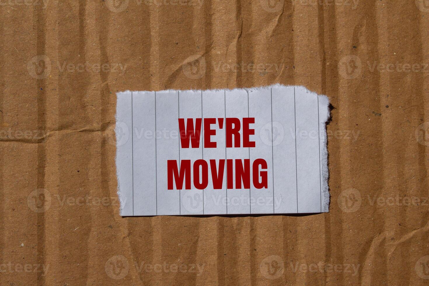 We are moving message written on ripped torn paper with cardboard background. Conceptual we are moving symbol. Copy space. photo