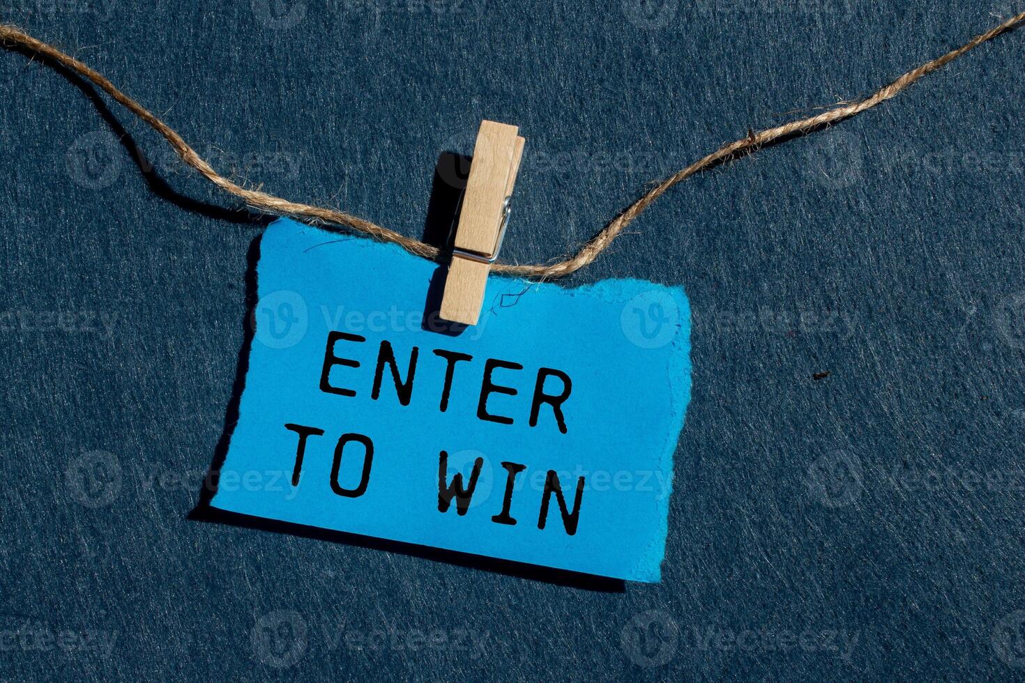 Enter to win message written on ripped blue torn paper piece with gray background. Conceptual enter to win symbol. Copy space. photo