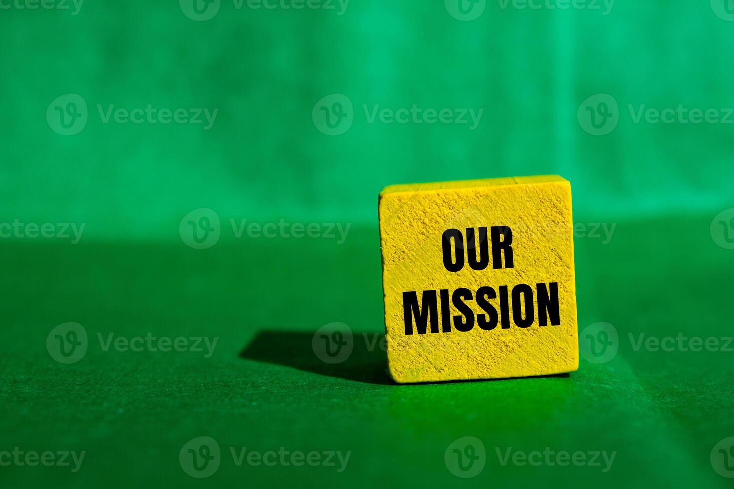 Our mission message written on yellow wooden cube with green background. Conceptual our mission symbol. Copy space. photo