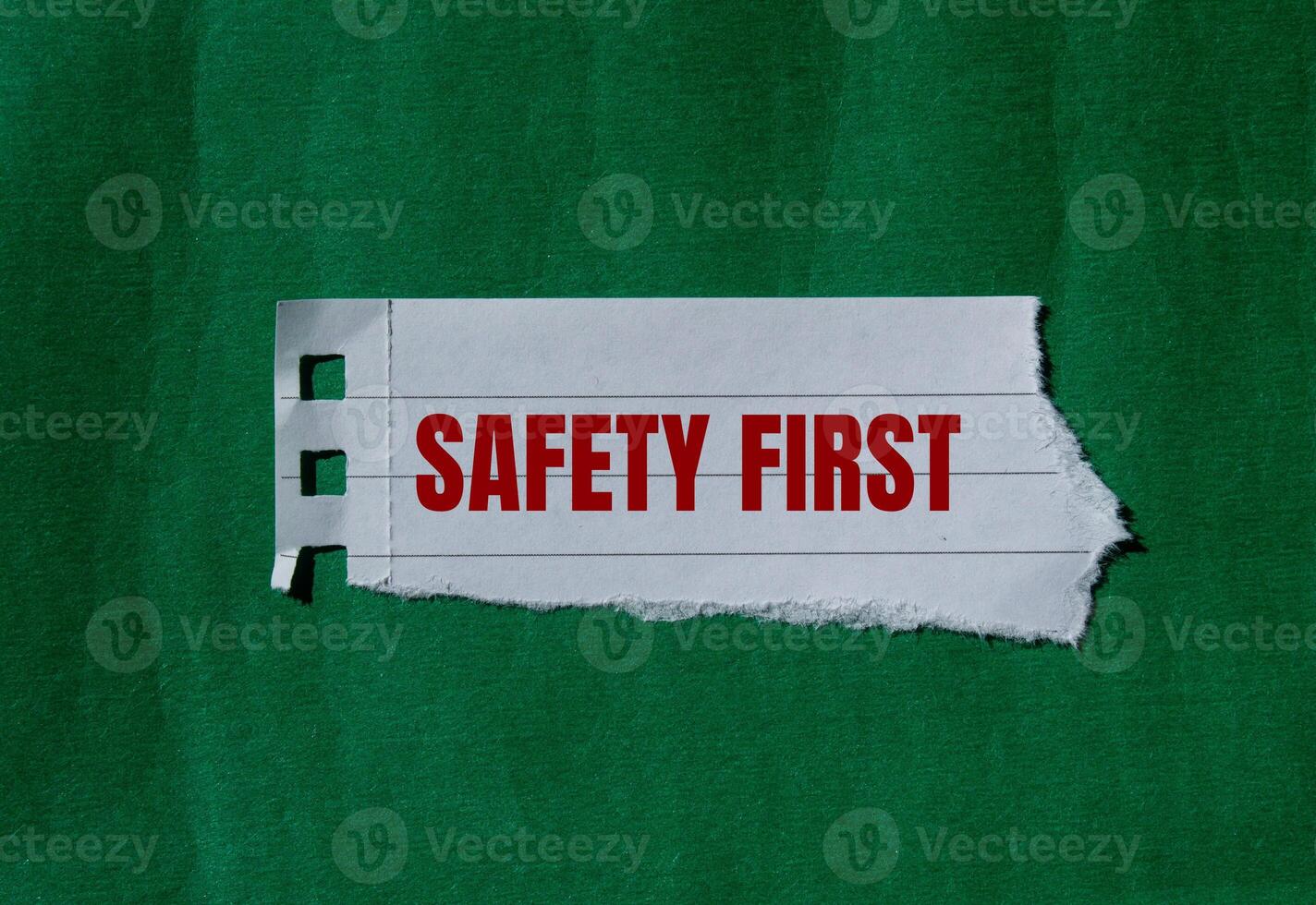 Safety first message written on ripped torn paper with green background. Conceptual safety first symbol. Copy space. photo