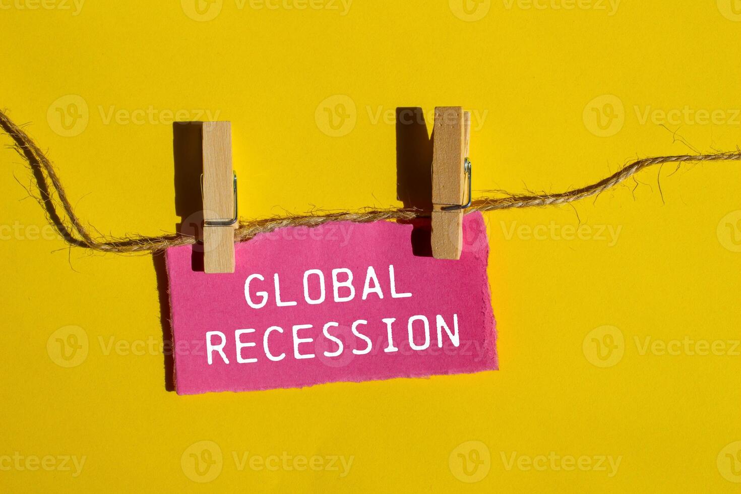 Global recession message written on ripped pink paper piece with yellow background. Conceptual global recession symbol. Copy space. photo