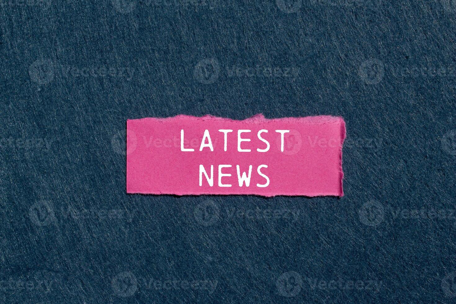 Latest news message written on ripped pink torn paper piece on gray background. Conceptual latest news symbol. Copy space. photo