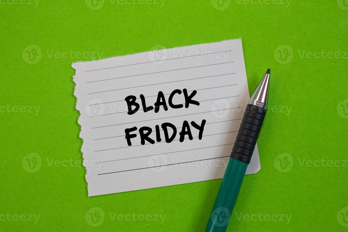 Black friday message written on ripped torn paper with a pen on green background. Conceptual black friday symbol. Copy space. photo