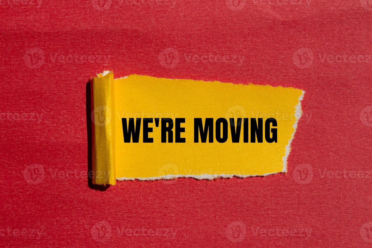 We are moving message written on ripped torn yellow paper with red background. Conceptual we are moving symbol. Copy space. photo