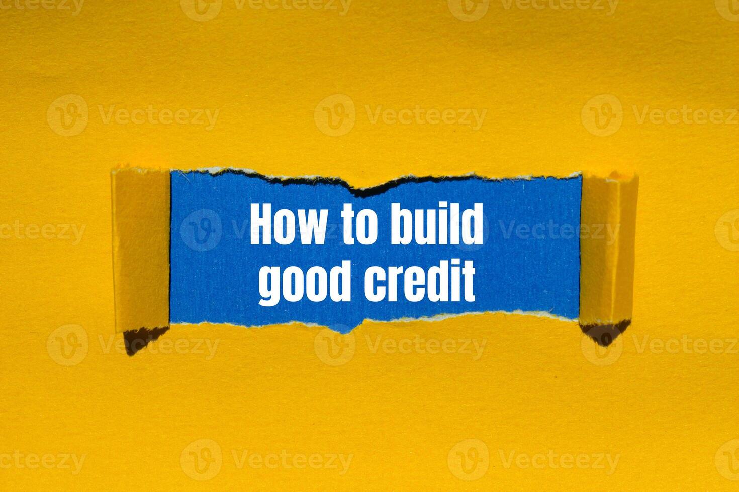 How to build good credit message written on ripped torn yellow paper with blue background. Conceptual how to build good credit symbol. Copy space. photo