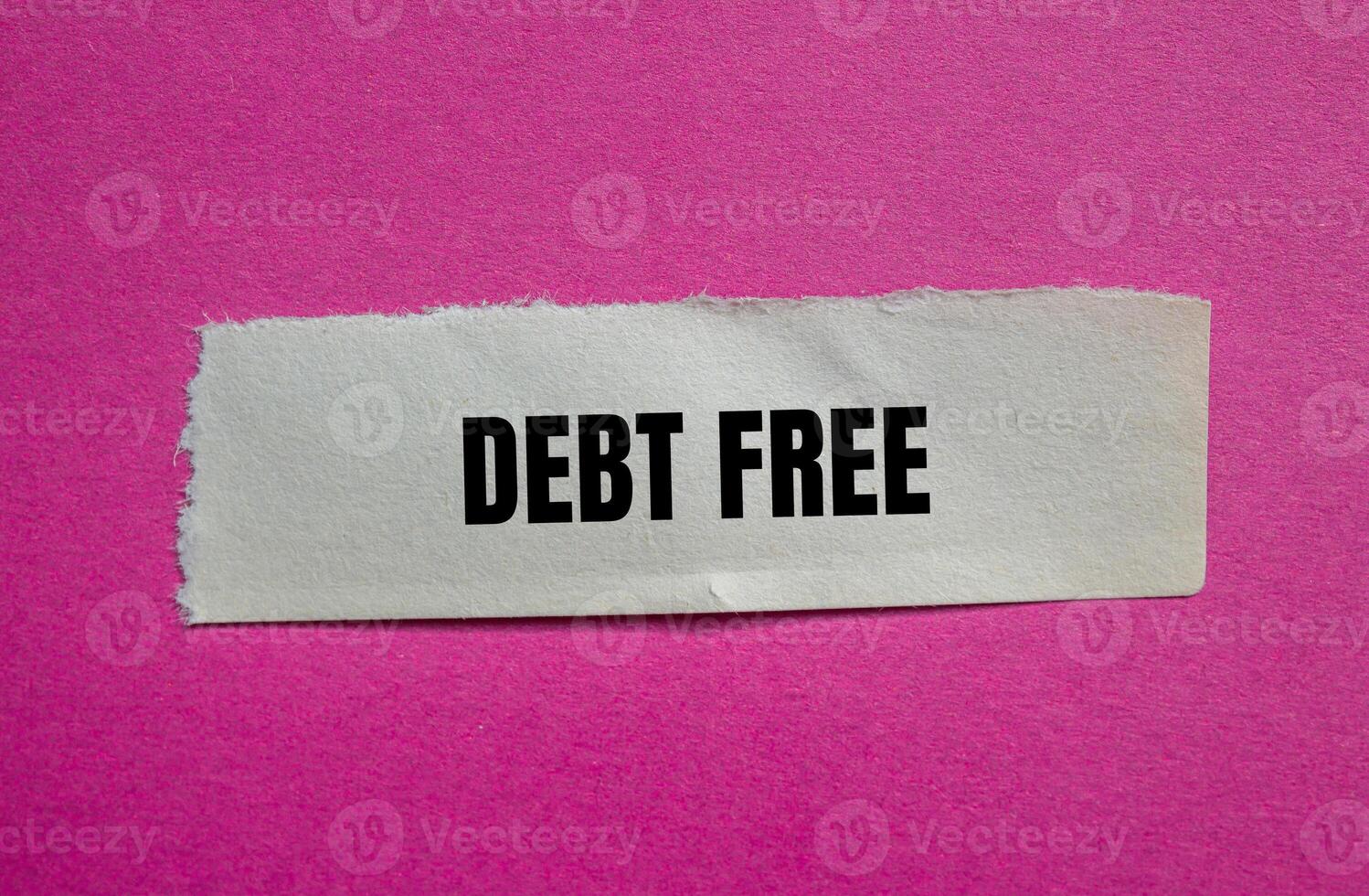 Debt free message written on ripped torn paper piece with pink background. Conceptual debt free symbol. Copy space. photo