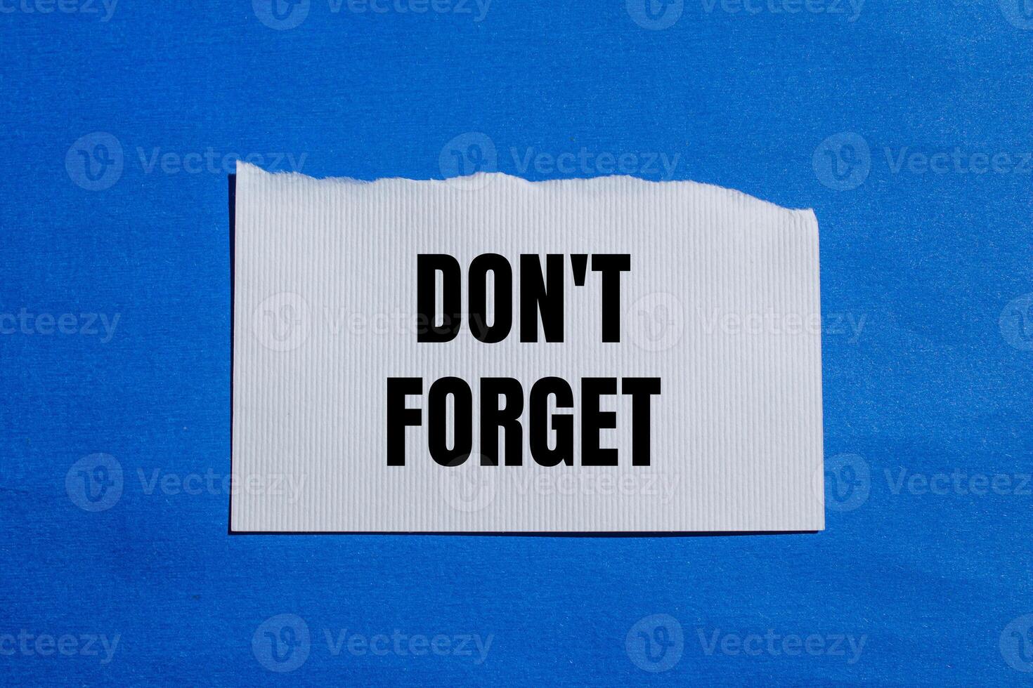Don't forget message written on ripped white torn paper piece with blue background. Conceptual don't forget symbol. Copy space. photo