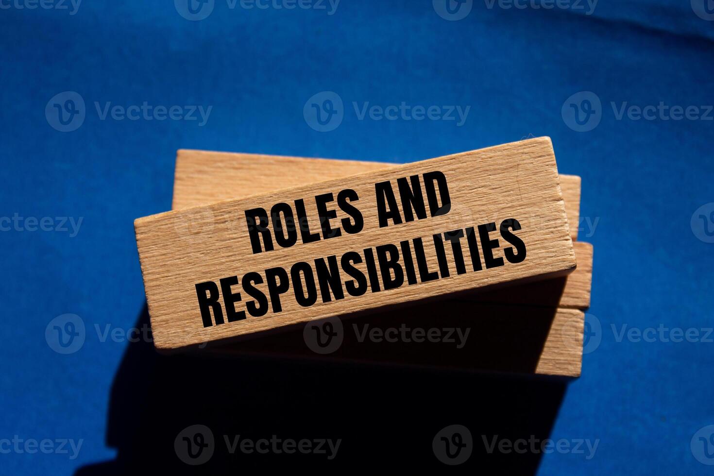 Roles and responsibilities message written on wooden blocks on blue background. Conceptual roles and responsibilities symbol. Copy space. photo