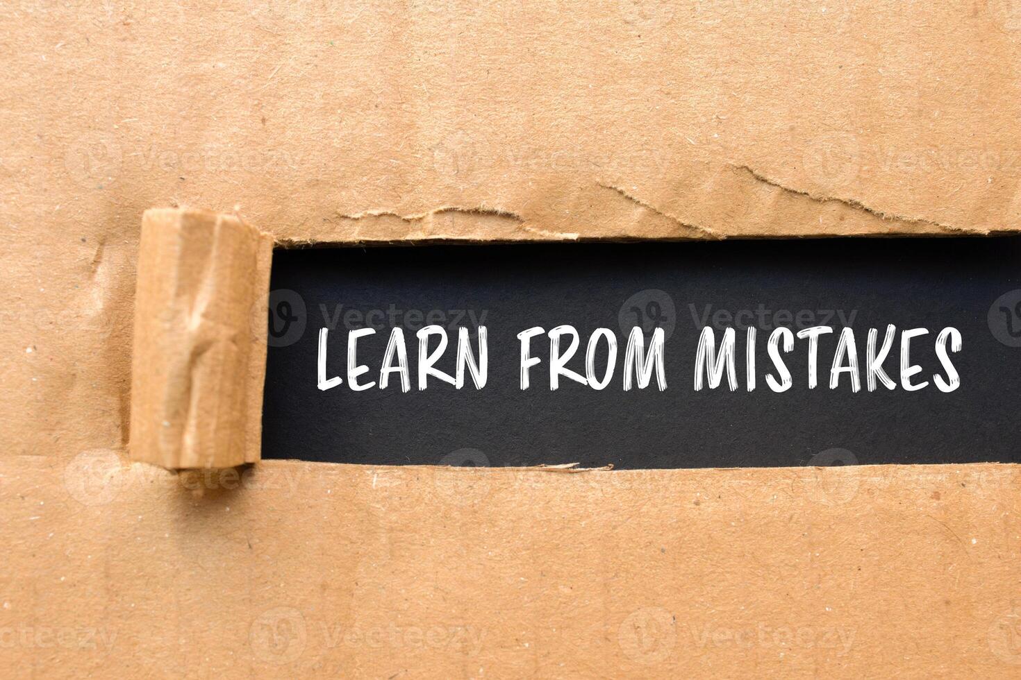 Learn from mistakes message written on ripped torn cardboard paper with black background. Conceptual learn from mistakes symbol. Copy space. photo