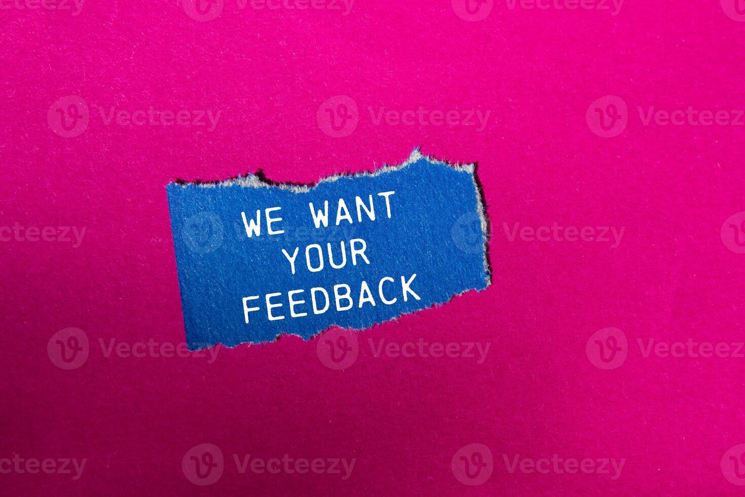 We want your feedback message written on ripped blue torn paper piece on pink background. Conceptual we want your feedback symbol. Copy space. photo