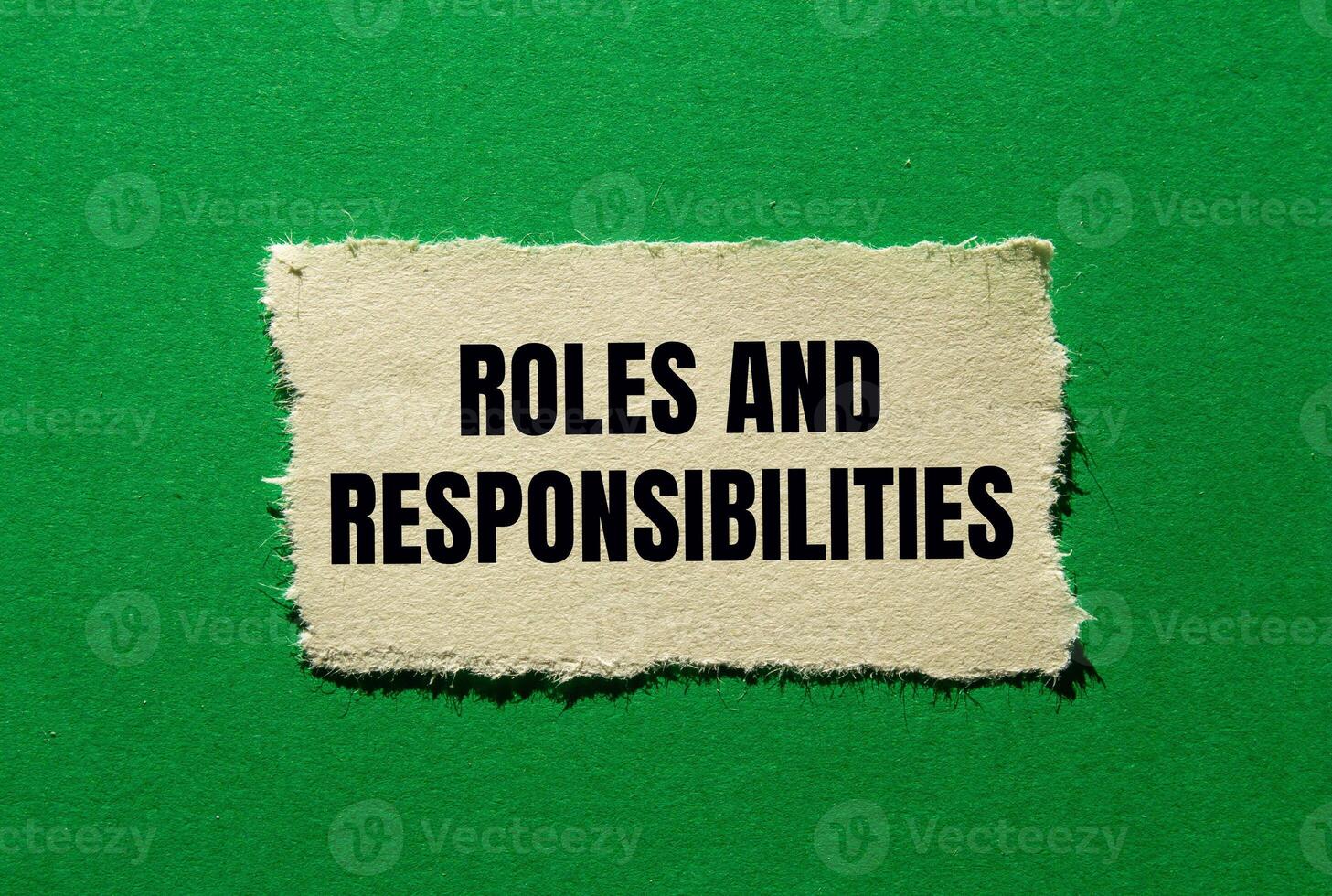 Roles and responsibilities message written on ripped torn paper piece on green background. Conceptual roles and responsibilities symbol. Copy space. photo