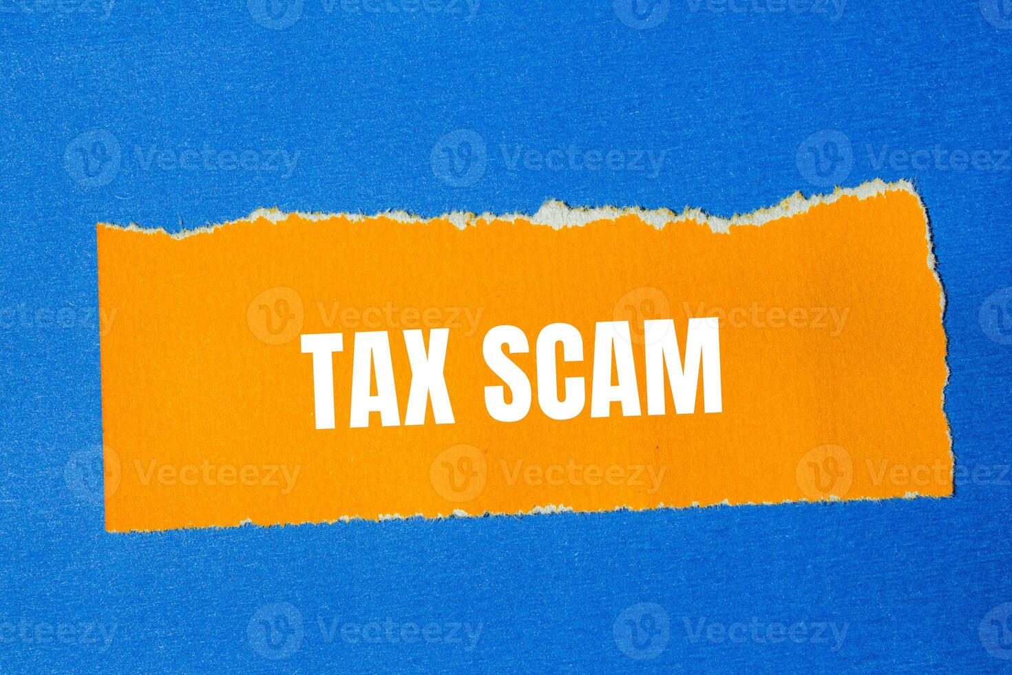 Tax scam message written on ripped torn orange paper with blue background. Conceptual tax scam symbol. Copy space. photo