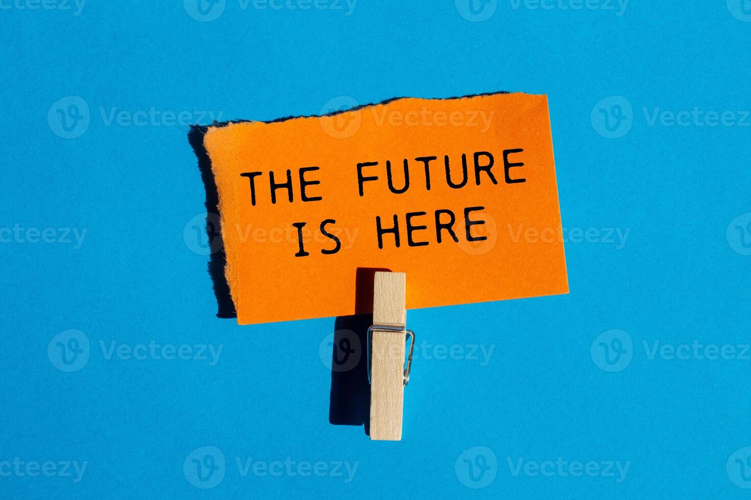 The future is here message written on ripped torn orange paper on blue background. Conceptual the future is here symbol. Copy space. photo