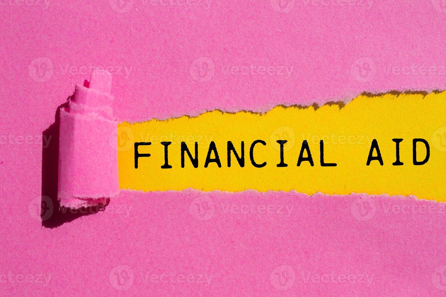 Financial aid message written on ripped torn pink paper with yellow background. Conceptual financial aid symbol. Copy space. photo