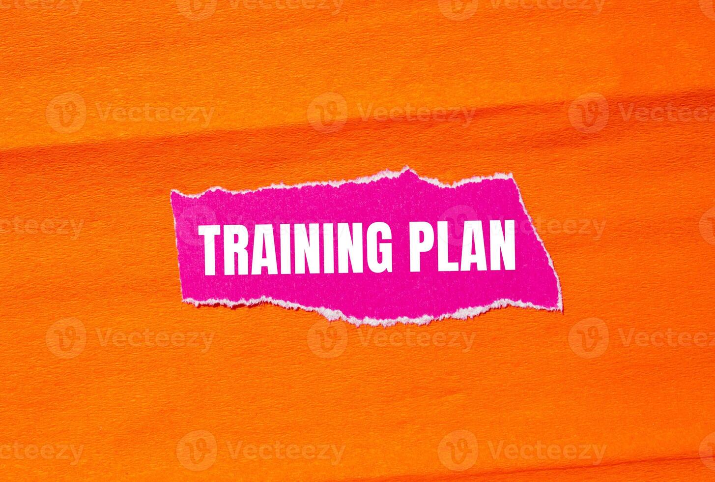 Training plan message written on ripped torn pink paper with orange background. Conceptual training plan symbol. Copy space. photo