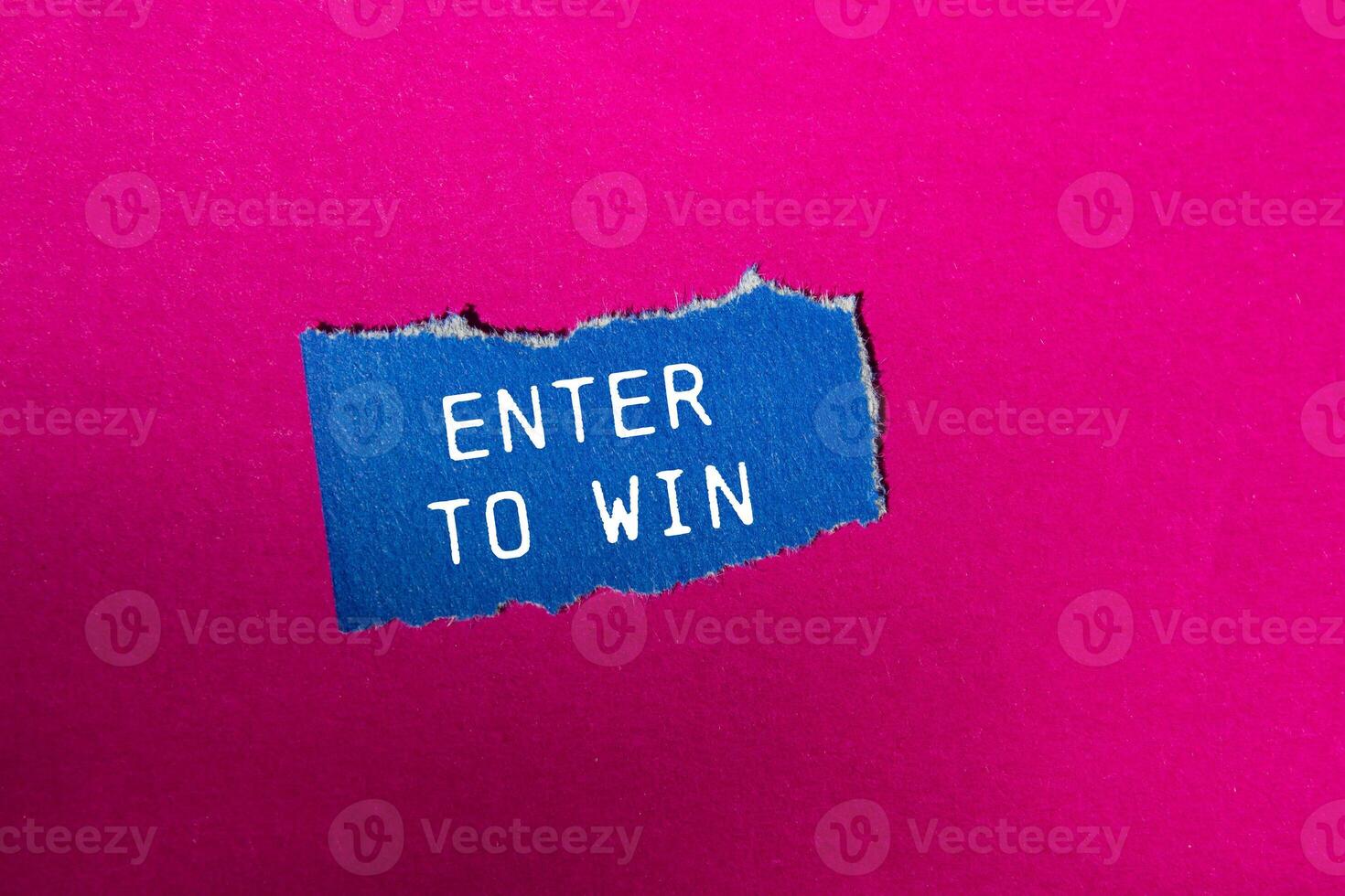 Enter to win message written on ripped blue torn paper piece on pink background. Conceptual enter to win symbol. Copy space. photo