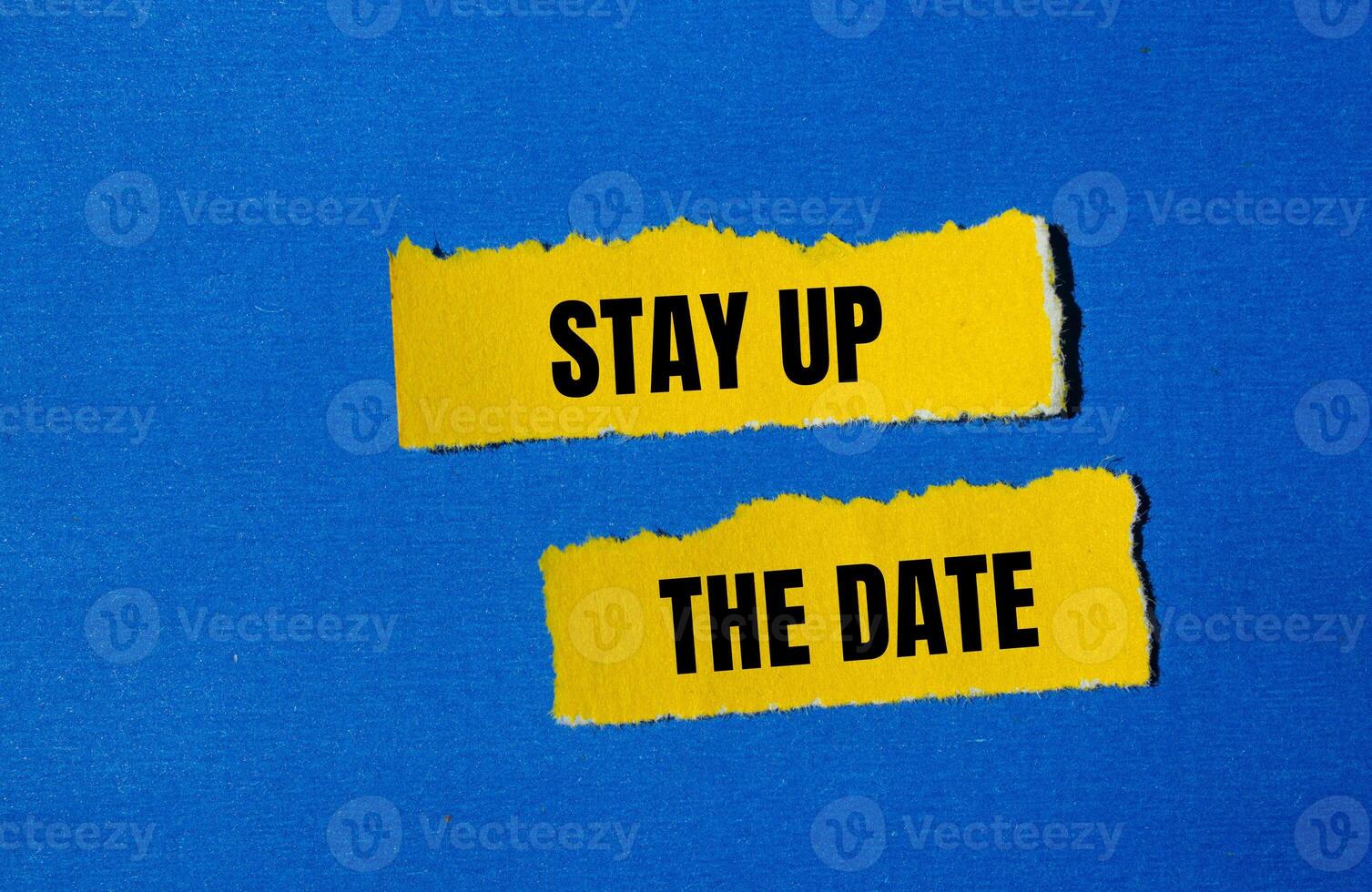 Stay up the date message written on ripped yellow torn paper pieces with blue background. Conceptual stay up the date symbol. Copy space. photo