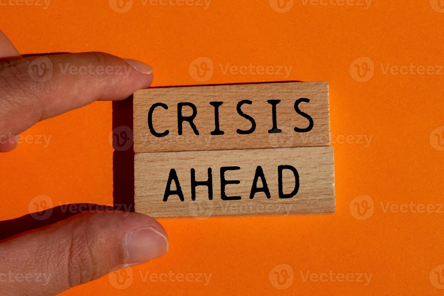 Crisis ahead message written on wooden blocks on orange background. Conceptual crisis ahead symbol. Copy space. photo