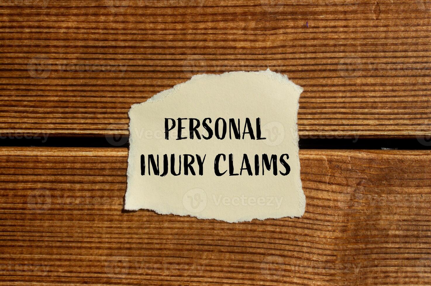 Personal injury claims message written on ripped torn paper with wooden background. Conceptual personal injury claims symbol. Copy space. photo