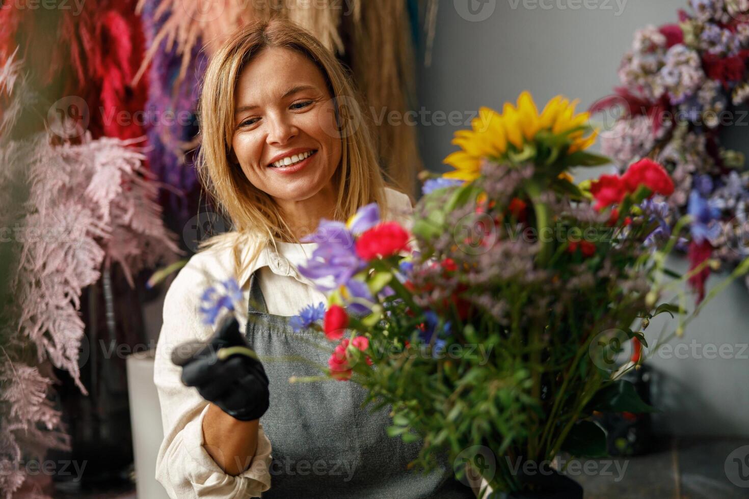 Professional smiling florist in flower shop make bouquet for holiday. Beautiful flowers composition photo