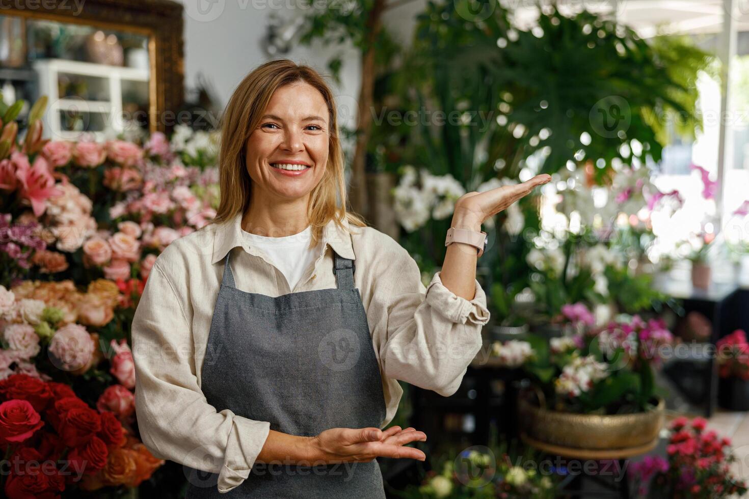 Smiling woman florist small business owner standing in own floral store and waiting for client photo